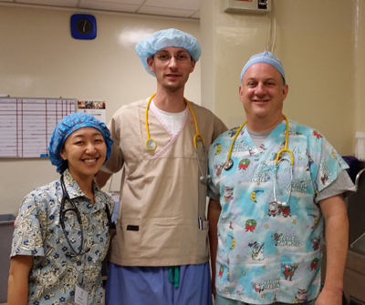 "Three medical professionals pose for a group photo in scrubs"
