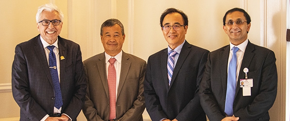 "Four department members in suits pose for a photo"