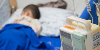 Blurred out photo of a child in a hospital bed and some medical equipment next to it