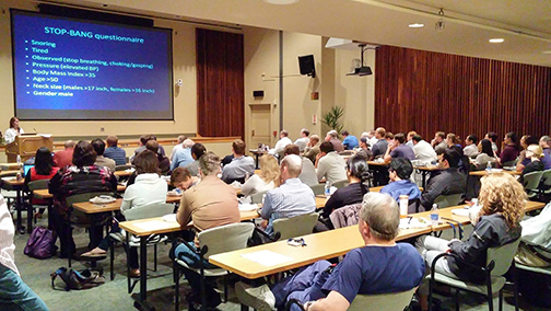 "A lecture hall full of people attending a class"