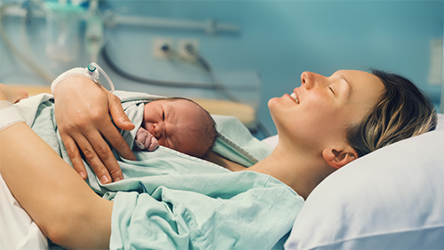 "A woman in a hospital bed holding a baby"