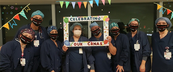 "Eight CRNAs pose with party favors and ribbons"
