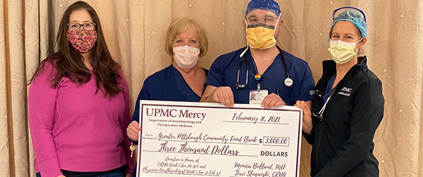 "UPMC Mercy staff pose with a large check for three thousand dollars"