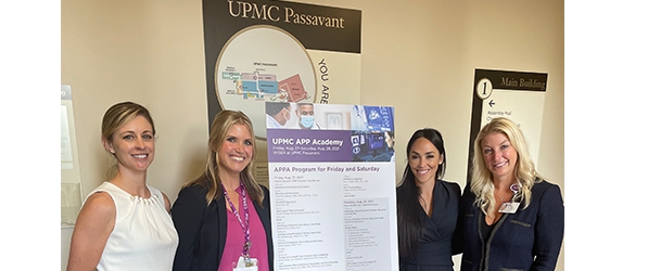 "Four department members posing next to poster"