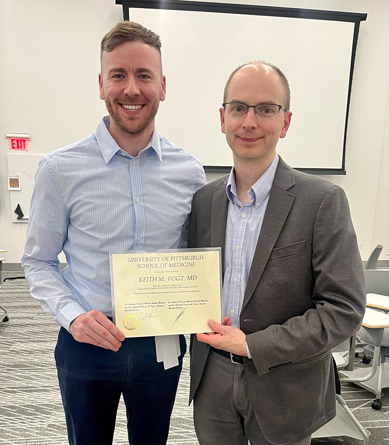 Two men stand side by side smiling; both are dressed in business casual attire. Taylor Duffy is on the left, and on the right is Keith M. Vogt, MD, holding an award certificate from the University of Pittsburgh School of Medicine.