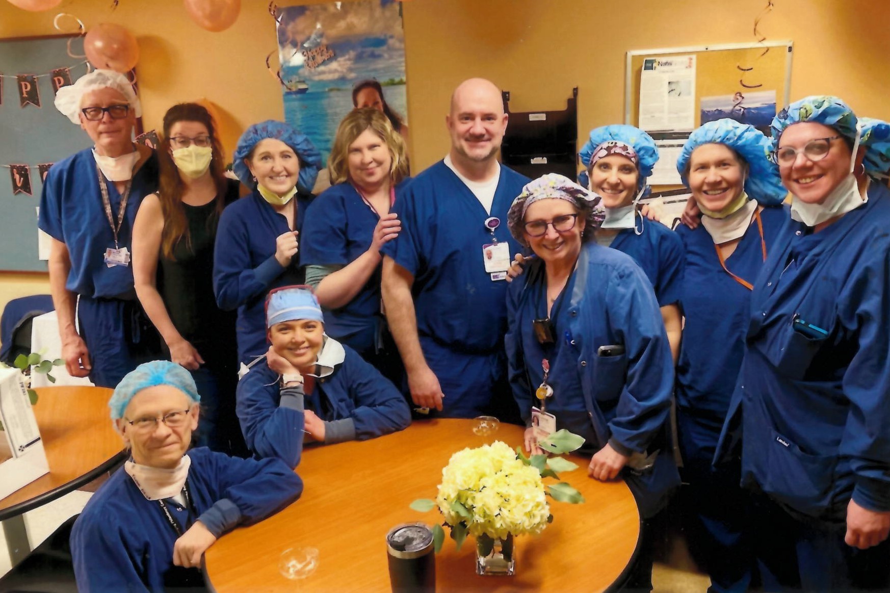 "A group of CRNAs in blue scrubs surrounding a table"