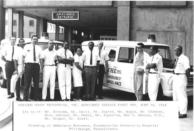 "A black and white photo of a group of people standing in front of an ambulance in the year 1968"