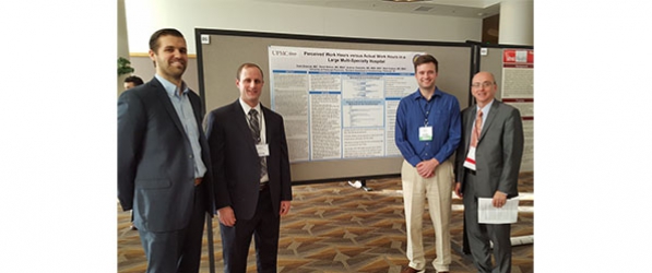 "Research team posing in front of a info board"