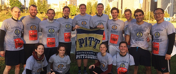 "Department members posing in uniform for the race. Two men in the middle are holding a towel with the Pitt block text logo."