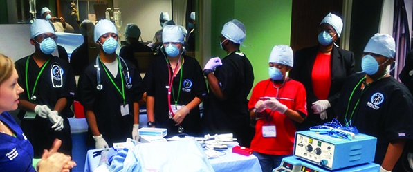 "A group of medical professionals standing around a table of instruments"