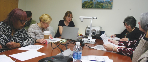 "Department staff sit around a table discussing papers"