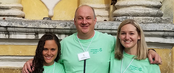 "Three department members pose in front of a building"