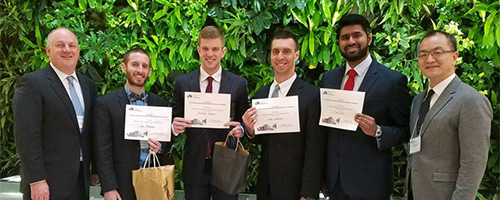 "A group of residents standing outside holding awards"