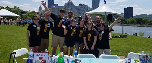 "A group of nurses posing outside with a backdrop of Pittsburgh and a river"