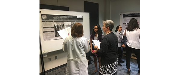 "Department members presenting in front of a poster"