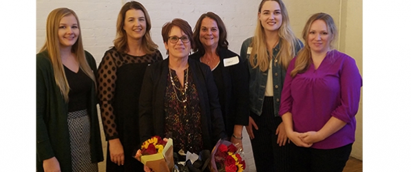 "A group of CRNAs posing for photo with two bouquets of flowers"