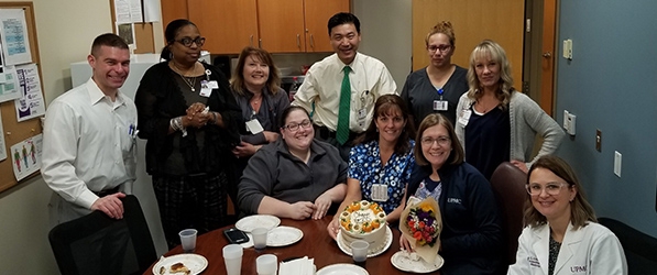 "Staff surrounding a table all smiling"