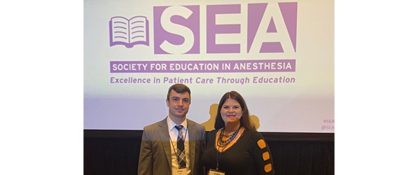 "Doctors Ondecko Ligda and Adams pose in front of a projected image of the SEA logo"