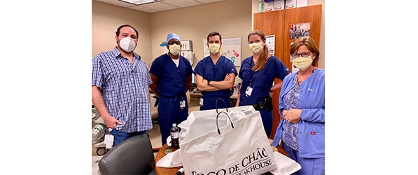 "Healthcare workers pose in a group around a bag from the restaurant Fogo de Chao"