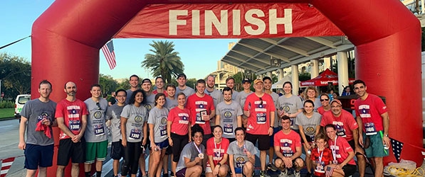 "Department members pose in running attire at the finish line"