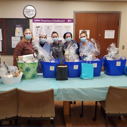 "MSICU staff posing with a table of gift baskets"