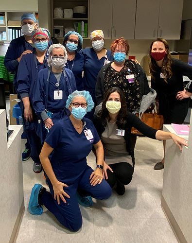"A group of medical professionals at UPMC Magee-Womens hospital pose for a photo in scrubs and masks"