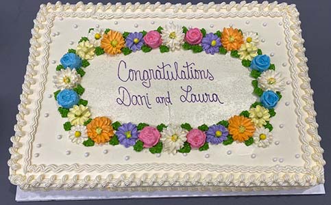 "A sheet cake that reads Congratulations Dani and Laura and is decorated with flowers"