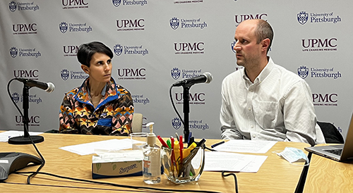 "Doctors Jarquin and Emerick at a table with microphones"