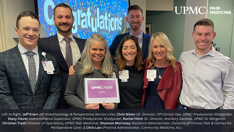 "UPMC staff in formal clothes pose in a group with an award"