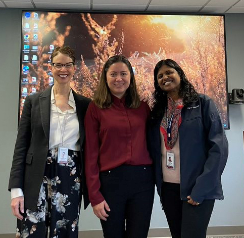 "Doctor Ibarra poses with two colleagues in front of a desktop screen projection"