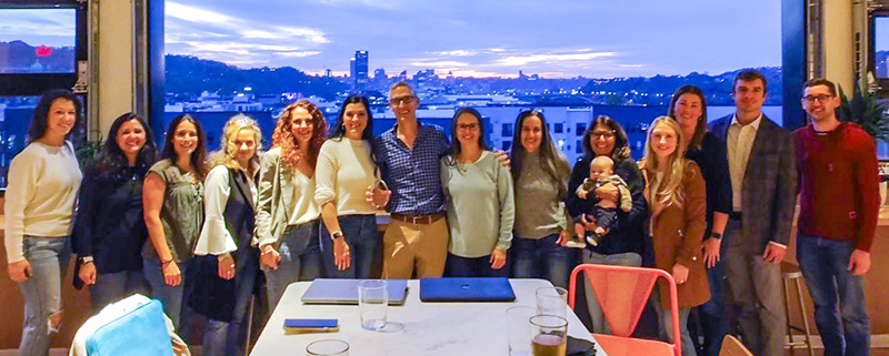 "A group photo of UPMC Children's Hospital staff at the award gathering, a sunset over the Pittsburgh skyline behind them"