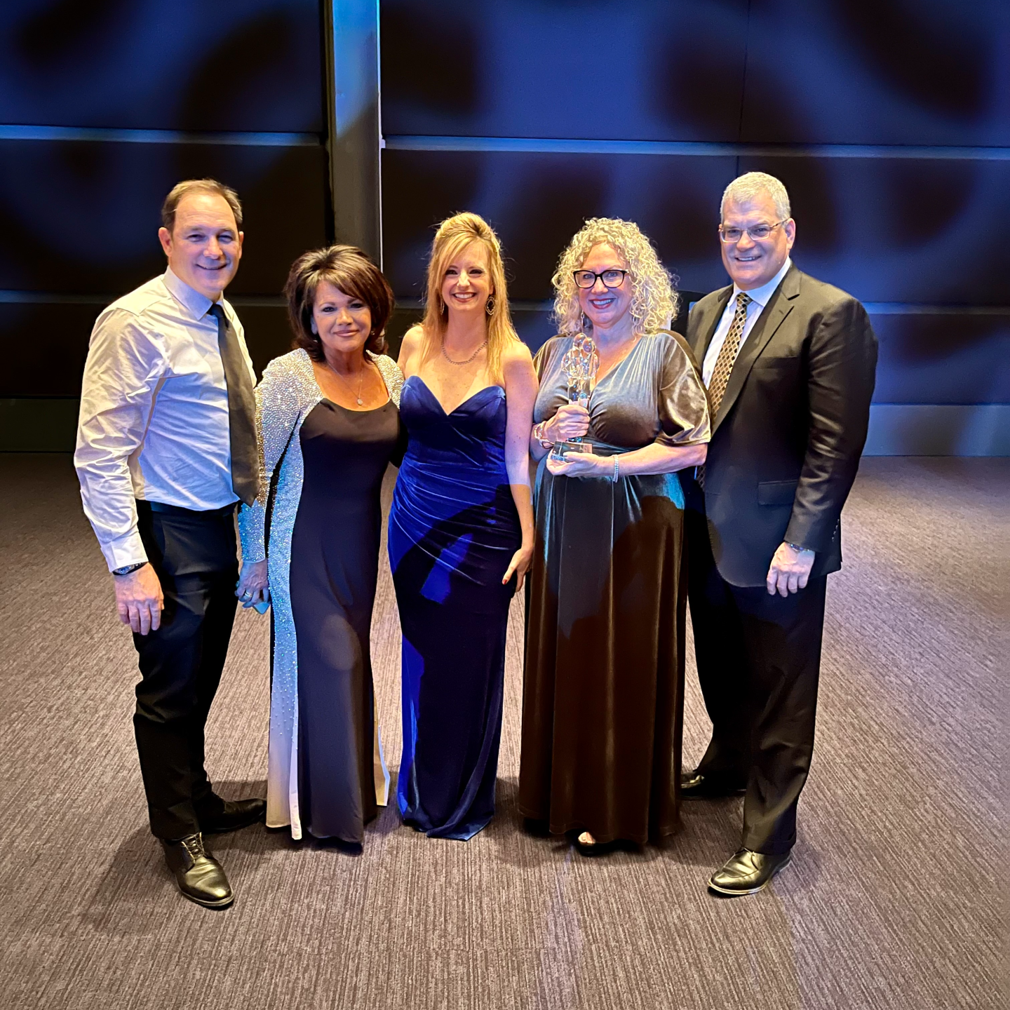 "Suellen in group with others in formal wear posing with award"