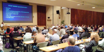 an auditorium full of attendees watch a journal club lecture