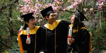 Photo of three alumni celebrating outside