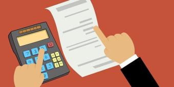 Graphic featuring a person completing their taxes using a piece of paper and a calculator