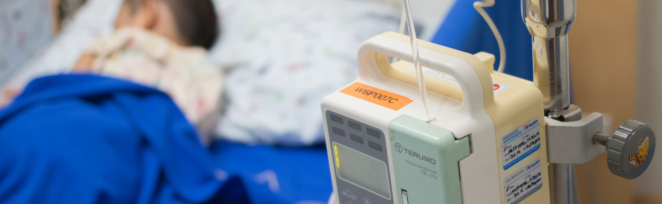 Blurred out photo of a child in a hospital bed and some medical equipment next to it